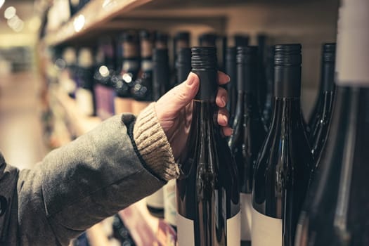 Woman choosing wine in market for winter new year's mulled wine