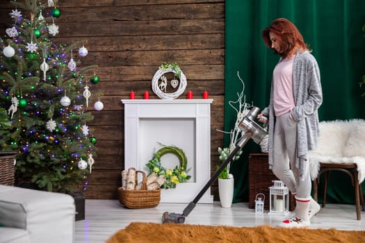 A young girl cleans the living room floor with a vacuum cleaner. The apartment decorated to relive Christmas.