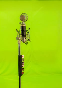 Vocal condenser microphone with wind screen isolated on green background.