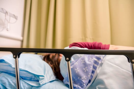 Woman patient lying on a bed in a hospital room.