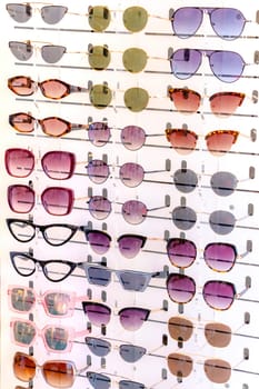 Stand with many sunglasses in a store of optics. Side close up view.