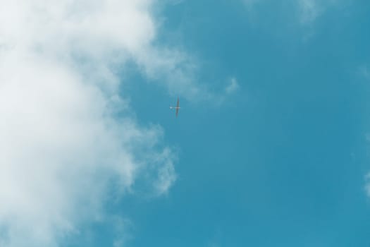 Glider gliding in blue sky from below.