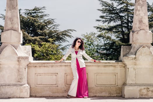 Woman park. Happy woman in classic white suit standing confidently looking away in old city park.