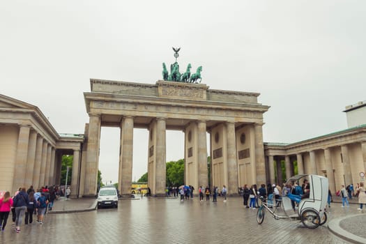 Berlin, Germany - May 16, 2017: Tourists at Brandenburg Gate. The Brandenburg Gate is a triumphal arch, a city gate in the center of Berlin. It is one of the most known sites in Berlin.