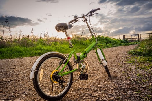 Bicycles parked on a dirt road during sunset.