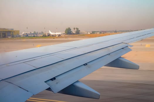 Airplane wing on the runway at ben gurion airport on sunrise