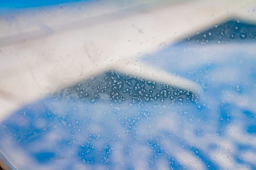 Frozen condensation of ice crystals on the window of an airplane with the wing in the back.