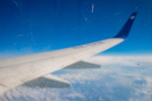 Frozen condensation of ice crystals on the window of an airplane with the wing in the back.