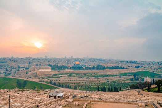 Panoramic view of Jerusalem old city and the Temple Mount during a dramatic colorful sunset. A view of the Tomb of the Prophets, Dome of the Rock and Al Aqsa Mosque from the Mount of Olives in Jerusalem, Israel.