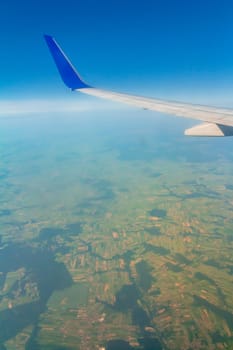 Airplane wing on the sky over land.