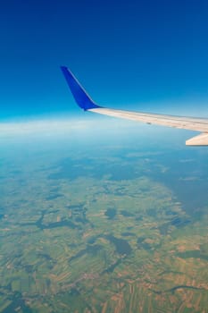 Airplane wing on the sky over land.