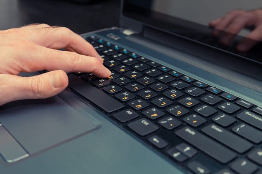 Man typing on a keyboard with letters in Hebrew and English - Laptop keyboard