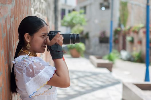 indigenous girl in traditional dress focuses reflex camera while sightseeing. High quality photo