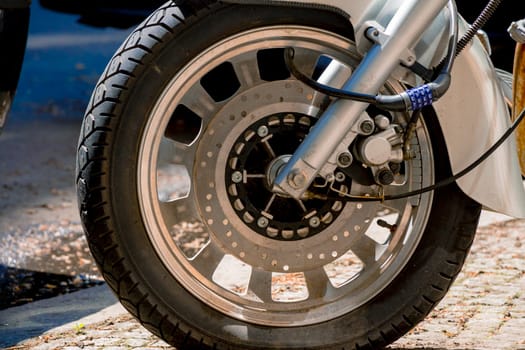 Security number padlock blocking motorcycle wheel on the street.