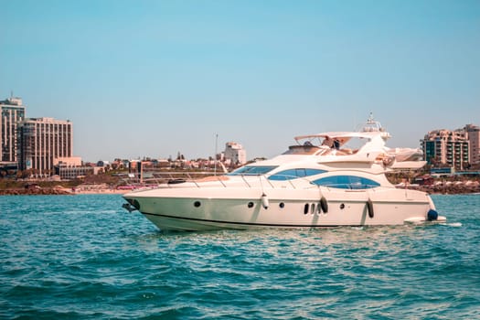 Yacht in the sea. Buildings in the background with blue sky.