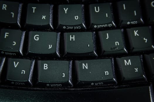 Keyboard with letters in Hebrew and English - Wireless keyboard - Top View - Close up - Dark atmosphere