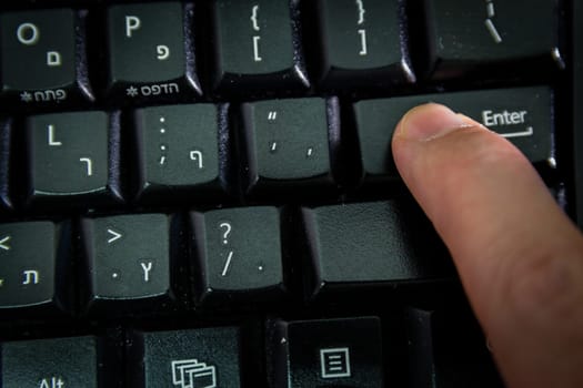 Man typing on a Wireless keyboard with letters in Hebrew and English - Press the Enter key - Top View - Dark atmosphere