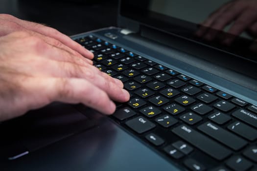 Man typing on a keyboard with letters in Hebrew and English - Laptop keyboard_Dark atmosphere