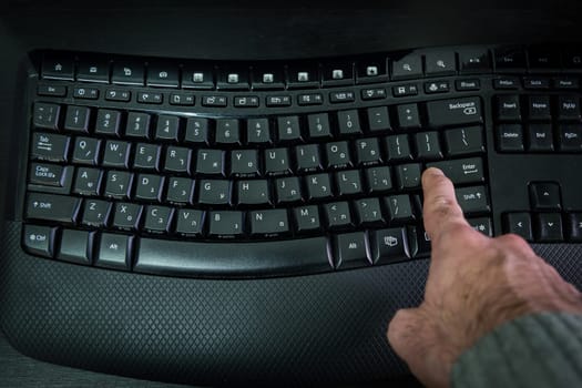 Man typing on a Wireless keyboard with letters in Hebrew and English - Press the Enter key - Top View - Dark atmosphere