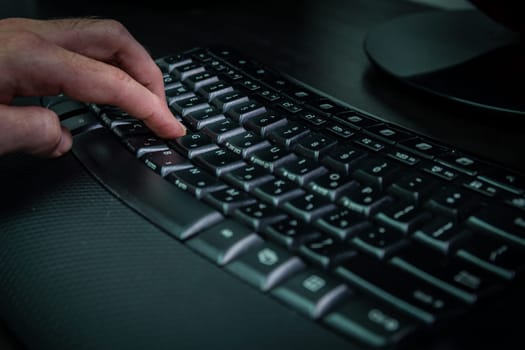 Man typing on a keyboard with letters in Hebrew and English - Wireless keyboard - Dark atmosphere