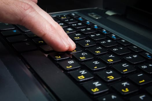 Man typing on a keyboard with letters in Hebrew and English - Laptop keyboard - Close up_Dark atmosphere