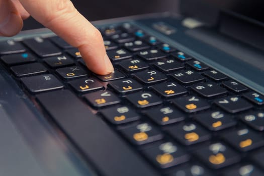 Man typing on a keyboard with letters in Hebrew and English - Laptop keyboard - Close up