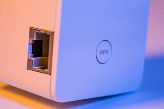 Closeup on WiFi repeater WPS button and ethernet socket. The device is in electrical socket on the wall. It help to extend wireless network in home or office.