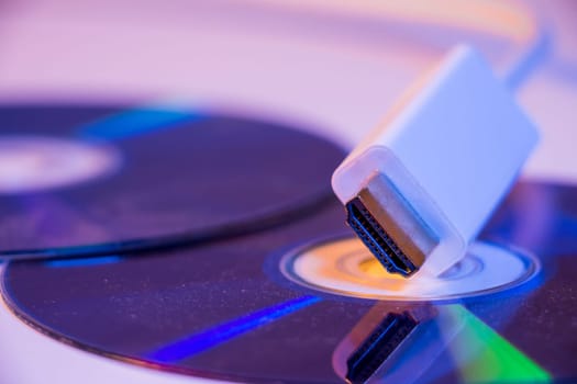 Closeup of white HDMI cable with it's reflection on blank disc.