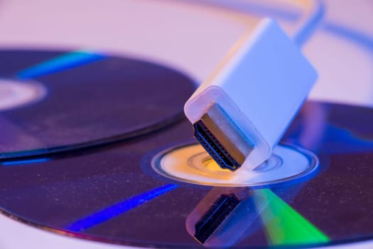 Closeup of white HDMI cable with it's reflection on blank disc.