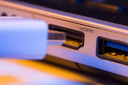 Closeup of HDMI cable plug inserted into port on the side of a laptop.