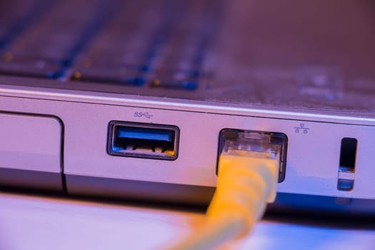 Closeup of Ethernet cable plug inserted into port on the side of a laptop.