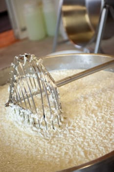 Cheesemaker cooking stirring italian bufalo organic milk in stainless steel caudrons, to produce ricotta cheese, italian food excellence worldwide export.