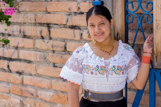 copyspace of young indigenous feminist woman in traditional dress looking at camera smiling and leaning on an iron gate. High quality photo