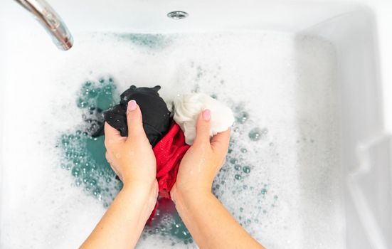 Female hands washing color clothes in basin