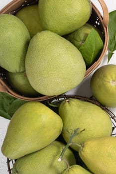 Fresh pomelo, pummelo, grapefruit, shaddock on white cement background in bamboo basket. Autumn seasonal fruit, top view, flat lay, tabletop shot.