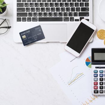 Concept of online payment with credit card with smart phone, laptop computer on office desk on clean bright marble table background, top view, flat lay