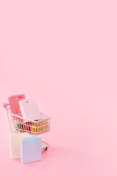 Annual sale shopping season concept - mini pink shop cart trolley full of paper bag gift isolated on pale pink background, blank copy space, close up