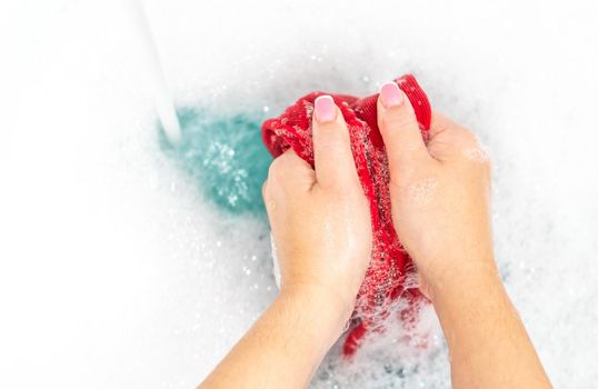 Female hands washing color clothes in basin