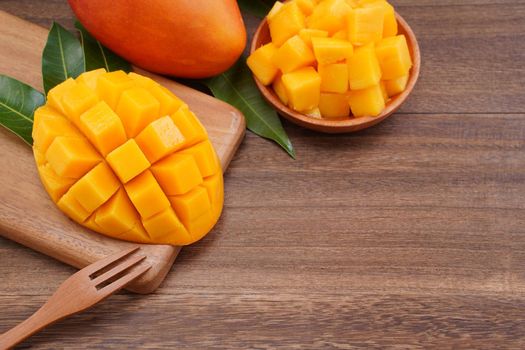 Fresh mango, beautiful chopped fruit with green leaves on dark wooden table background. Tropical fruit design concept. Flat lay. Top view. Copy space