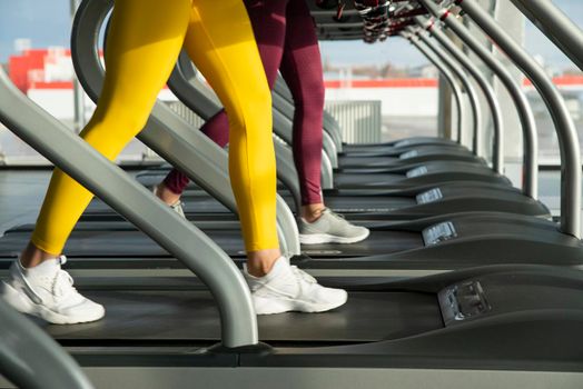 Two young women running on treadmill in a gym