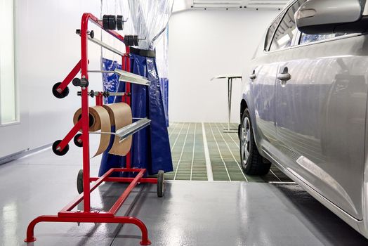 Painting the white car body in the spray booth in the body repair workshop