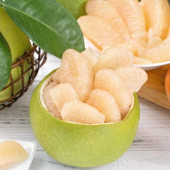 Fresh peeled pomelo, grapefruit, shaddock on bright wooden table background. Seasonal fruit for Mid-Autumn Festival, close up, copy space.