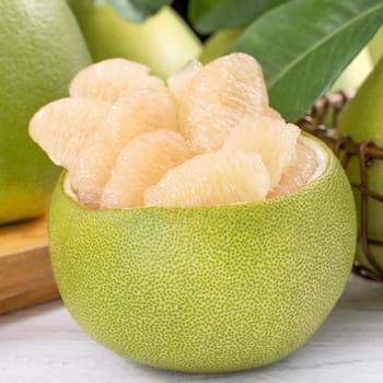 Fresh peeled pomelo, grapefruit, shaddock on bright wooden table background. Seasonal fruit for Mid-Autumn Festival, close up, copy space.