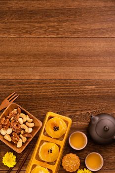 Mid-Autumn Festival holiday concept design of moon cake, mooncakes, tea set on dark wooden table with copy space, top view, flat lay, overhead shot