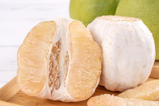 Fresh peeled pomelo, pummelo, grapefruit, shaddock on bright wooden table background. Seasonal fruit for Mid-Autumn Festival, close up, copy space.