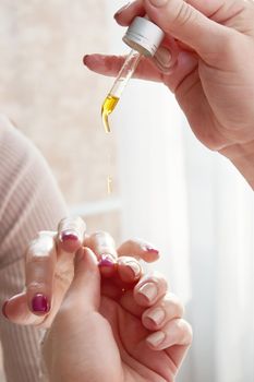 Moisturizing oil for cuticles. The woman cares for hands and nails.