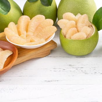 Fresh peeled pomelo, pummelo, grapefruit, shaddock on bright wooden table background. Seasonal fruit for Mid-Autumn Festival, close up, copy space.