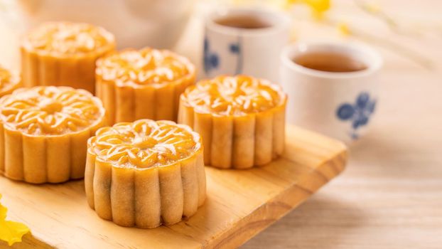Mid-Autumn Festival holiday concept design of moon cake,mooncakes,tea set on bright wooden table and serving plate with copy space, close up.