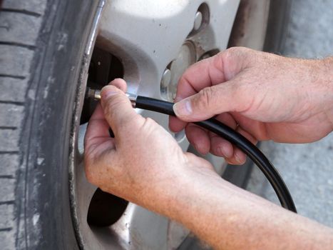 male hands screw the hose of the car pump to the wheel close-up