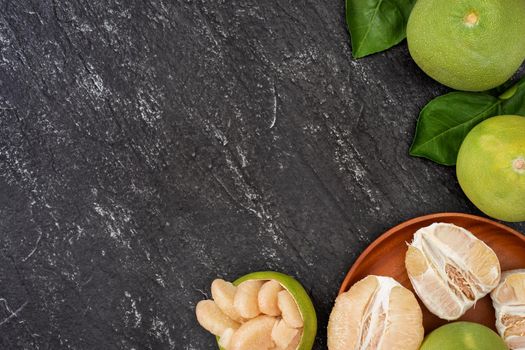 Fresh peeled pomelo, pummelo, grapefruit, shaddock on dark background in bamboo basket. Autumn seasonal fruit, top view, flat lay, tabletop shot.